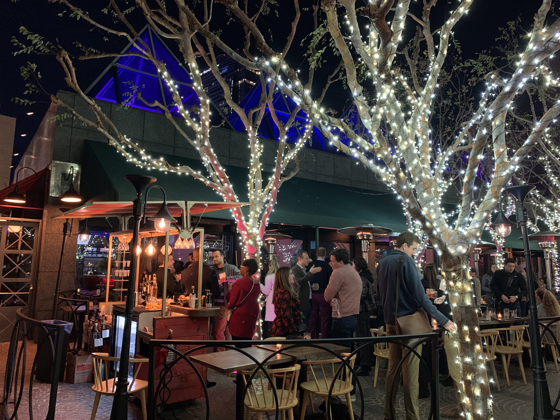 Guests filling the illuminated Strada courtyard beside the operating cart bar